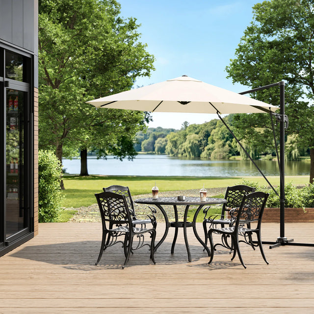 Beige ronde zweefparasol boven een tuintafel met vier stoelen op een houten terras