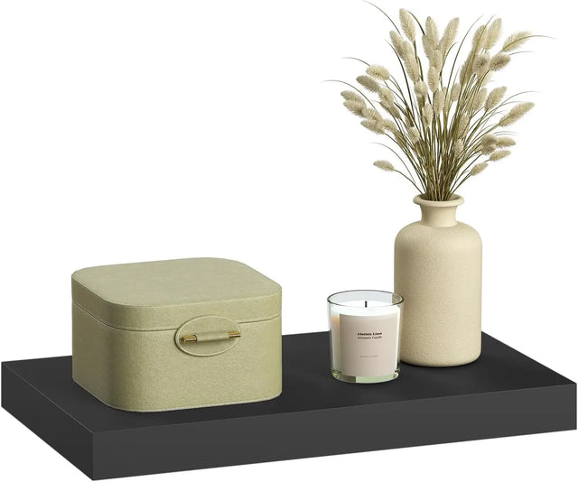 Zwarte zwevende wandplank met een opbergdoos, kaars en vaas met droogbloemen